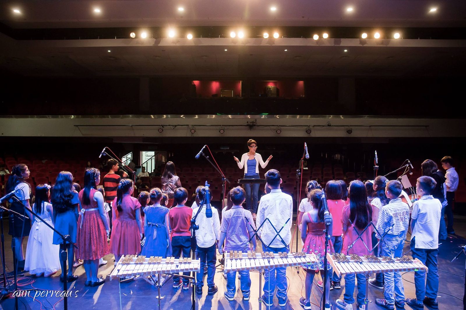 A conductor leading students in performance, facing the camera
